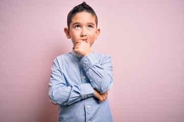 Wall Mural - Young little boy kid wearing elegant shirt standing over pink isolated background with hand on chin thinking about question, pensive expression. Smiling with thoughtful face. Doubt concept.