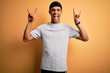 © Krakenimages.com - Handsome african american sportsman doing sport wearing sportswear over yellow background shouting with crazy expression doing rock symbol with hands up. Music star. Heavy music concept.