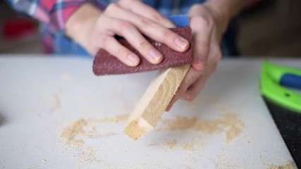 Wall Mural - Woman handles a wooden block with sandpaper, closeup