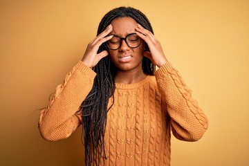 Sticker - Young african american smart woman wearing glasses and casual sweater over yellow background with hand on head for pain in head because stress. Suffering migraine.