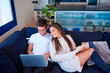 © Jordi Janau/ADDICTIVE STOCK - High angle of young man browsing laptop and woman reading interesting book while resting together on comfortable couch in modern living room
