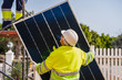 © Javier De La Torre/ADDICTIVE STOCK - Back view of mature experienced male technician in uniform and helmet standing with solar panel near yellow building while working on installation of renewable energy system