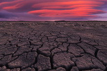 From Above Of Drought Cracked Lifeless Ground Under Colorful Cloudy Sky At Sunset Time
