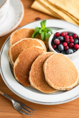 Wall Mural - Buckwheat pancakes on plate served with summer berries, wooden table background. Healthy breakfast food