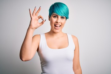 Young beautiful woman with blue fashion hair wearing casual t-shirt over white background smiling positive doing ok sign with hand and fingers. Successful expression.