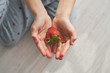 © PHILIPPE DEGROOTE/ADDICTIVE STOCK - From above top view of anonymous kid sitting on floor and demonstrating fresh strawberry on summer day at home