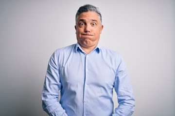 Poster - Middle age handsome grey-haired business man wearing elegant shirt over white background puffing cheeks with funny face. Mouth inflated with air, crazy expression.