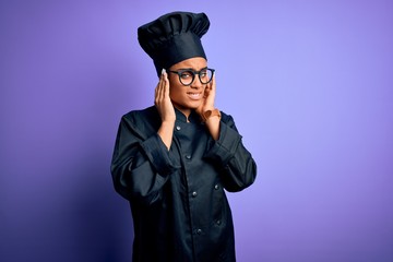 Poster - Young african american chef girl wearing cooker uniform and hat over purple background covering ears with fingers with annoyed expression for the noise of loud music. Deaf concept.