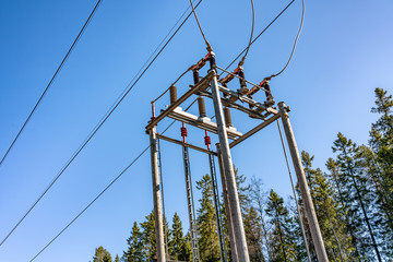 Wooden utility four poles pylon construction  for electrical 3 phase energy and distribution. Electrical power distribution from higher voltage electrical line to lower for local needs.