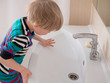 © galitsin - Happy blonde boy washes hands with soap. Child playing with bar of soap and water in sunny bathroom with window. Water activities for kids. Hygiene and skin care for brood. Bathroom interior