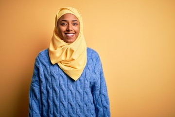 Wall Mural - Young African American afro woman wearing muslim hijab over isolated yellow background with a happy and cool smile on face. Lucky person.