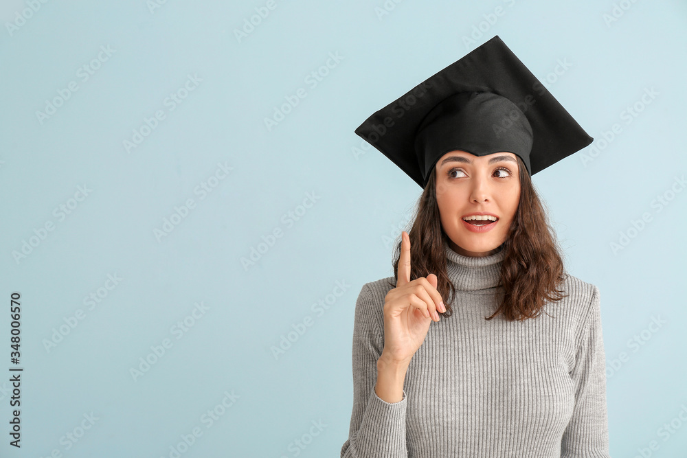 Female graduating student with raised index finger on light background