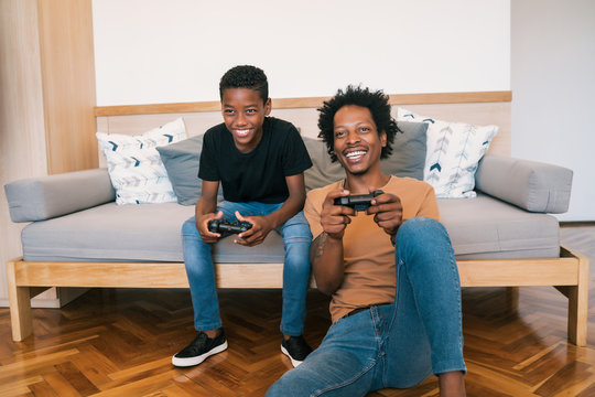 Father and son playing video games together at home.