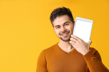 Canvas Print - Young man with tablet computer on color background