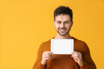 Canvas Print - Young man with tablet computer on color background