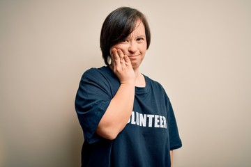 Wall Mural - Young down syndrome volunteer woman wearing social care charity t-shirt touching mouth with hand with painful expression because of toothache or dental illness on teeth. Dentist concept.