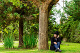 Fototapeta  - Beautiful woman sitting under a tree on a winter day