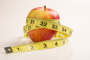 Measuring tape wrapped around a red apple. Diet concept