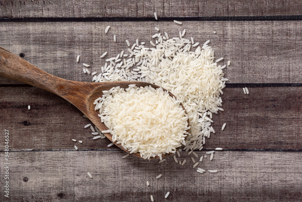 Ladled Rice Closeup uncooked dry Thai jasmine rice in wooden ladle and overflow ...