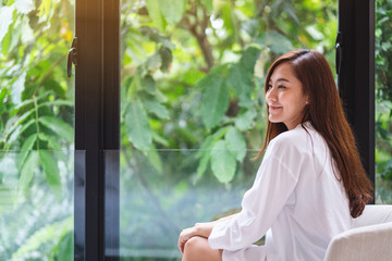 Portrait image of a beautiful asian woman with green nature outside the window