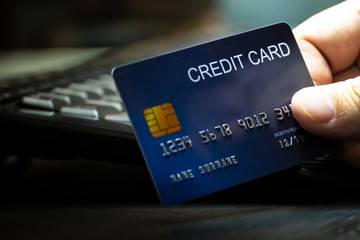 Poster - close up Shallow focus hand hold Credit Card on Computer keyboard. Background for E-commerce and online shopping concept.