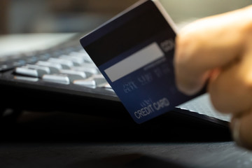 Poster - close up Shallow focus hand hold Credit Card on Computer keyboard. Background for E-commerce and online shopping concept.