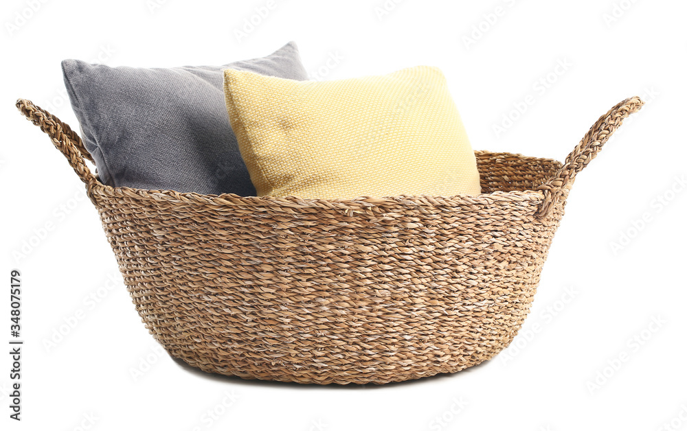 Wicker basket with pillows on white background