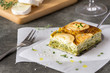 Zucchini pie or quiche with goat cheese on wooden cutting board. Slice of goat cheese near it. Healthy vegetarian food, lunch or dinner. 