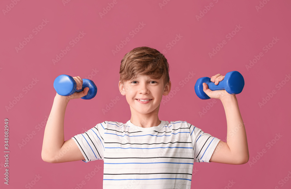 Sporty little boy with dumbbells on color background