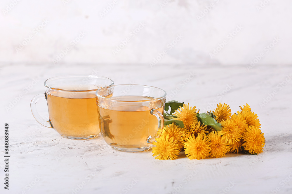 Cups of healthy dandelion tea on light background