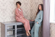 © satura_ - Two female sisters or friends relaxing at the living room. Girls in stylish pajamas. Quarantine and stay at home concept.