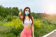 Fitness Girl, young woman in protective sterile medical mask on her face looking at camera an showing thumb up sign. Ready to work out during covid 19, coronavirus pandemic