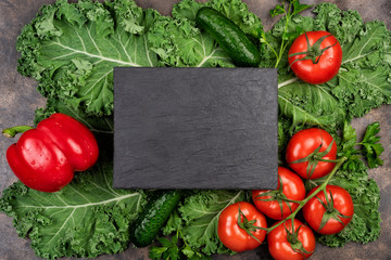 Kale salad leaf and red tomatoes, pepper, cucumbers with water drops on an old rustic metal tray. Green nature background. Black stone chalk board for copy space