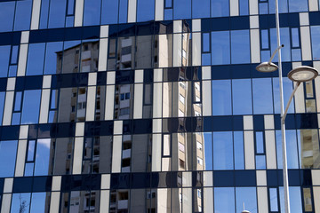 Modern glass building with older building and blue sky reflection