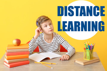 Wall Mural - Cute little boy doing homework at table. Concept of distance learning