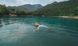 © vitaliymateha - Traveler woman swimming on back in beautiful mountain lake with clear blue water against mountains. beautiful scenery, people in nature and travel concept