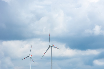 Two windmills and clody sky behind them