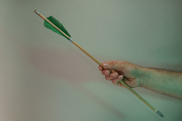 Poster - Hand holding old green arrows in the color light. Beautiful old arrow minimal in neon light. Minimalism retro style concept. Background pattern for design.