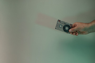 Poster - Hand holding audio cassette tape in the color light. Beautiful minimal in neon light. Minimalism retro style concept. Background pattern for design.