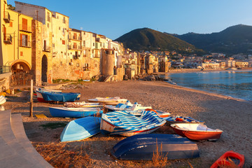 Canvas Print - Boats on the beach and sunny houses in coastal city Cefalu at sunset, Sicily, Italy