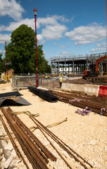 A large construction site with building equipment, digger and men with hard hats and yellow jackets