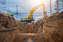 Backhoe Excavator Digging A Trench For Installation Water Pipeline Underground At Construction Site.