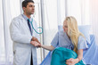 © nationkp - male doctor wearing stethoscope on ear and check the pulse of a female patient sitting on a hospital bed