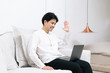 © Gengwit - Attractive asian male working with computer laptop at home.  Video conferencing call via computer