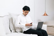 © Gengwit - Attractive asian male working with computer laptop at home. Analyzing online data to success business