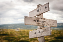 Be Happy Now Text Engraved On Old Wooden Signpost Outdoors In Nature. Quotes, Words And Illustration Concept.