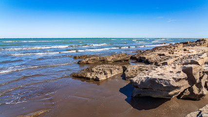 Wall Mural - Rocky sea coast with blue water and small waves