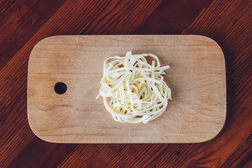 Soft straw cheese Chechil on plate on wooden table