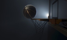 An Action Shot Of A Black And Gold Basketball Teetering On The Rim Of A Regular Basketball Hoop Dramatically Spotlit From Behind On An Isolated Dark Background - 3D Render