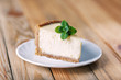 © Ivan Kmit - Slice of classic New York cheesecake with a sprig of mint on a plate on a wooden table. The concept of bakery and sweet cakes desserts
